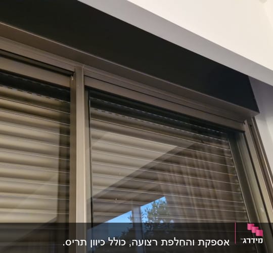 תריסים סגורים על חלון זכוכית עם וילון בצד